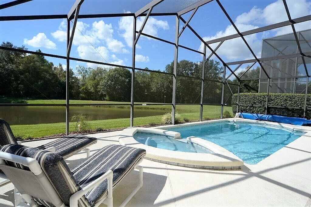 A screened outdoor pool area with lounge chairs and a view of a golf course.