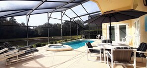 A covered outdoor area with a pool, lounge chairs, and a table with chairs. - 4630 4 Bedroom Private Pool Home, Cumbrian Lakes (Kissimmee)