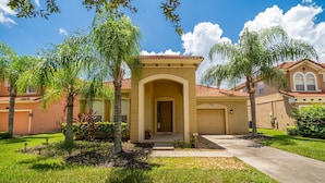 A residential building with a central entrance, surrounded by well-maintained lawns and palm trees. - Bella Vida Resort Luxury Pool Home Game Room View! (Kissimmee)