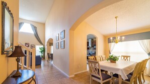 A dining area with a table and chairs, a chandelier, and a staircase leading to another room.