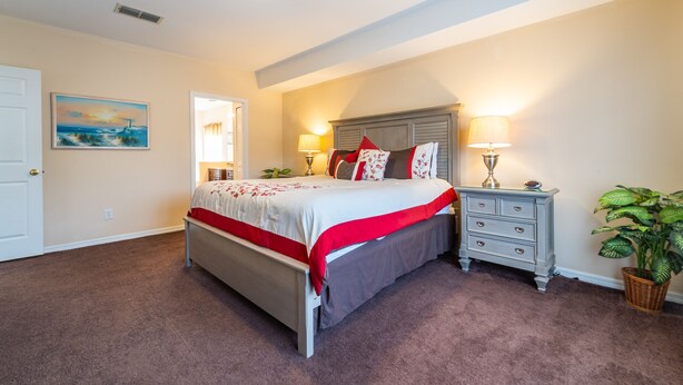 A bedroom with a bed, bedside tables, a lamp, and a painting on the wall.