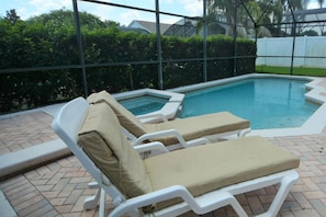 A swimming pool with two lounge chairs and a glass enclosure. - 2509ljt 4-bedroom Pool Home Near Disney Orlando (Kissimmee)