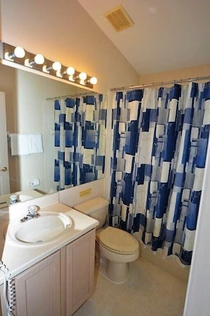 A bathroom with a sink, toilet, and a shower curtain with a blue and white pattern. - 2509ljt 4-bedroom Pool Home Near Disney Orlando (Kissimmee)