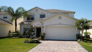 A two-story house with a garage, a paved driveway, and a well-maintained lawn. - 4636 5-bed Disney Area Pool Home, Cumbrian Lakes (Kissimmee)