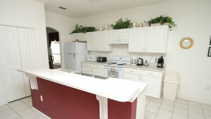 A modern kitchen with white cabinets, a red island, and a microwave. - 4636 5-bed Disney Area Pool Home, Cumbrian Lakes (Kissimmee)