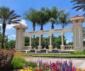 A sign for Emerald Island Resort with a classical architectural style, featuring columns and a decorative archway. - Huge 6-bed Emerald Is Resort- Elite Vacation Homes (Kissimmee)