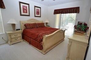 A bedroom with a large bed, two bedside tables, a dresser, and a window with curtains. - Huge 6-bed Emerald Is Resort- Elite Vacation Homes (Kissimmee)