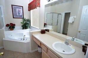 A bathroom with a bathtub, a sink, a large mirror, and a potted plant. - Huge 6-bed Emerald Is Resort- Elite Vacation Homes (Kissimmee)