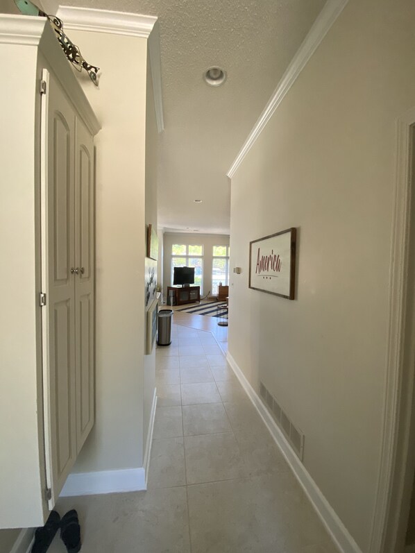 A hallway with a door on the left, a trash can, and a framed sign on the right.