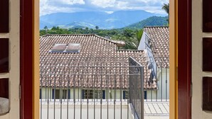 Une vue à travers une porte ouverte, donnant sur un balcon dont le sol est recouvert de carreaux et qui est agrémenté de rampes en métal.