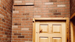 A wooden door in a hallway with a brick wall.