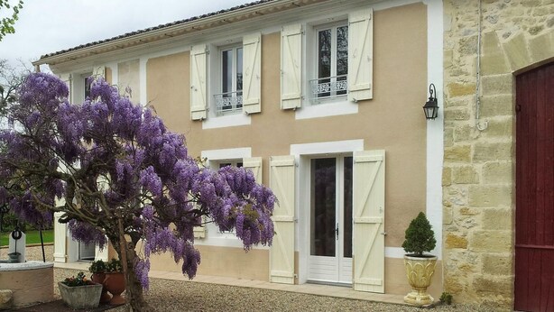 Un bâtiment à deux étages, doté de volets blancs et d’une façade en pierre.