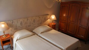 Un lit double avec une tête de lit, deux tables de chevet avec des lampes et une armoire en bois.