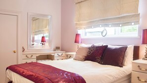 A bedroom with a bed, bedside tables, a dresser, a mirror, and a window with curtains.