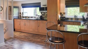 A modern kitchen with wooden cabinets, a central island, and two bar stools.