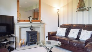 A living room with a fireplace, leather sofa, and a television.