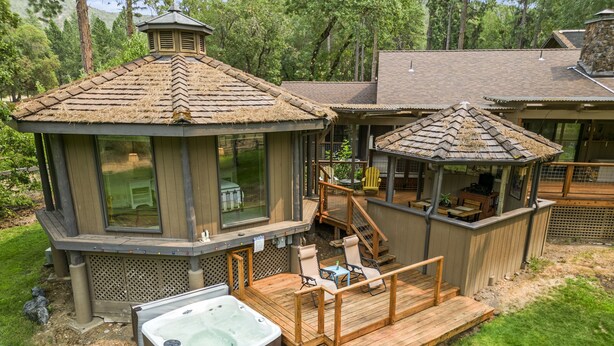 A hot tub on a wooden deck with a covered seating area and a gazebo.