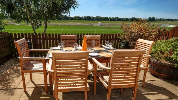 An outdoor dining area with a wooden table and chairs, surrounded by a wooden fence. - 47 Wetherby Way (Stratford-upon-Avon)