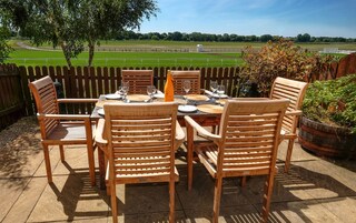 An outdoor dining area with a wooden table and chairs, surrounded by a wooden fence.