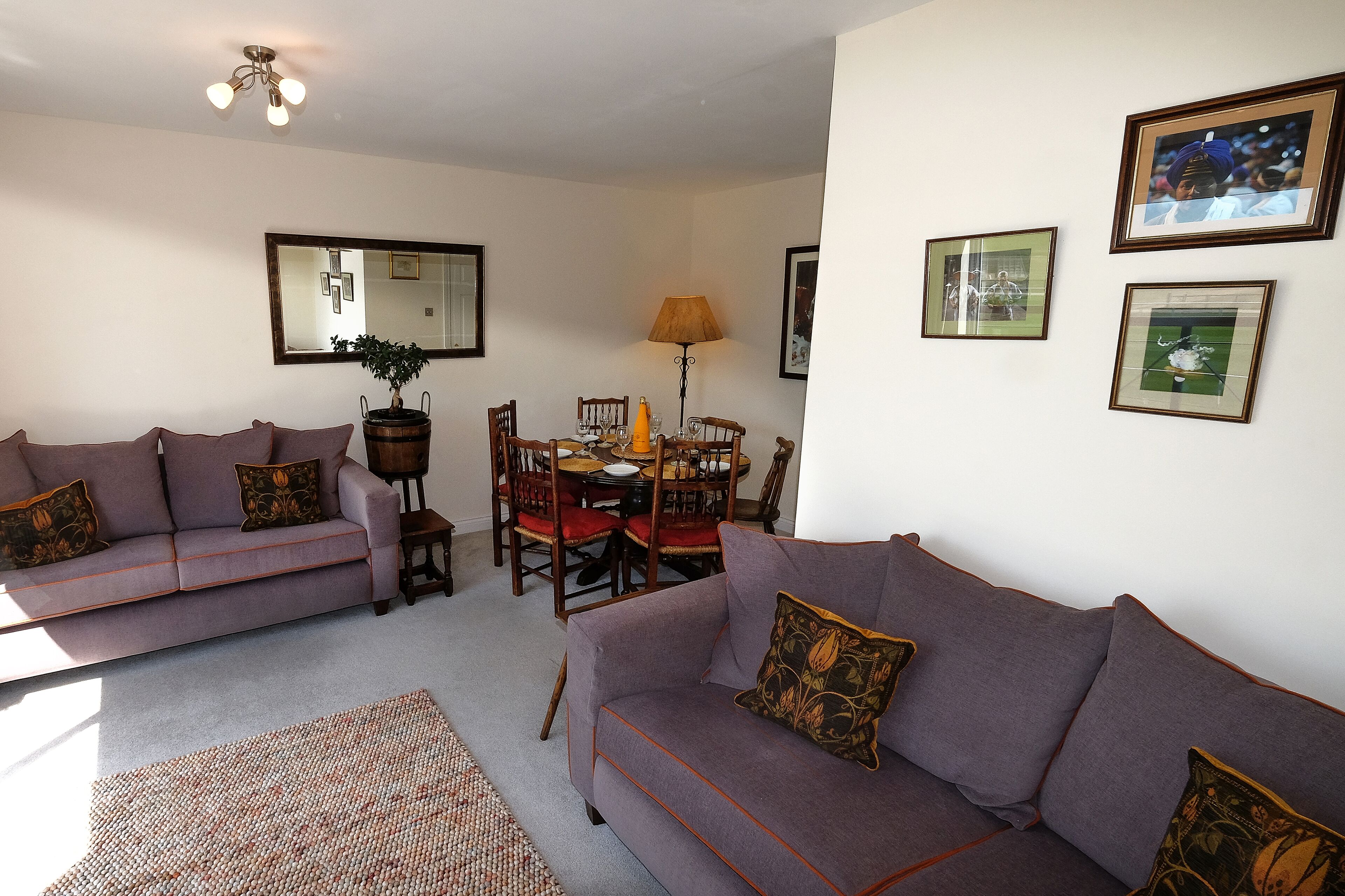 A living room with two sofas, a dining table, chairs, and a lamp.