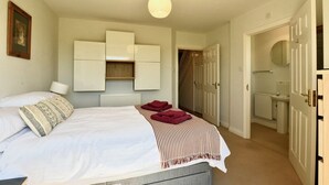 A bedroom with a bed, a radiator, a wardrobe, and a bathroom visible through an open door. - 47 Wetherby Way (Stratford-upon-Avon)