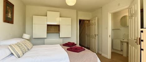 A bedroom with a bed, a radiator, a wardrobe, and a bathroom visible through an open door.