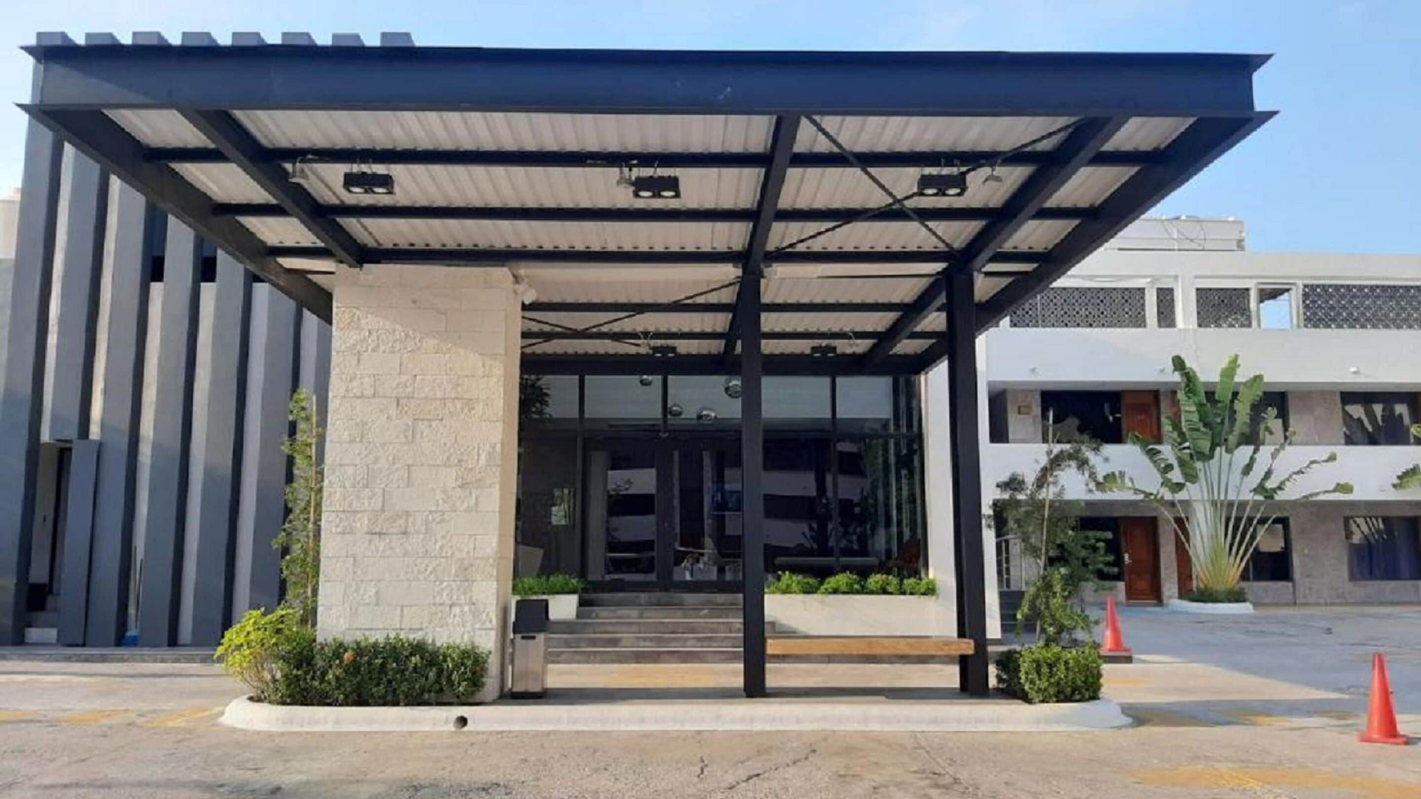 A modern building with a covered entrance, a stone pillar, and a bench.