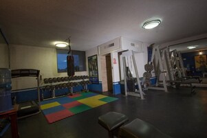 Un gimnasio con equipo de levantamiento de pesas, un saco de boxeo y un dispensador de agua.