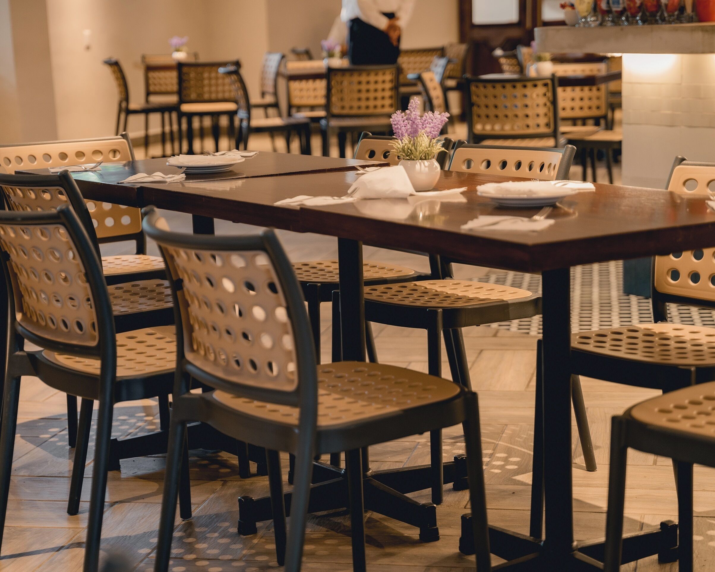 Un restaurante con mesas y sillas redondas, algunas con respaldo trenzado.