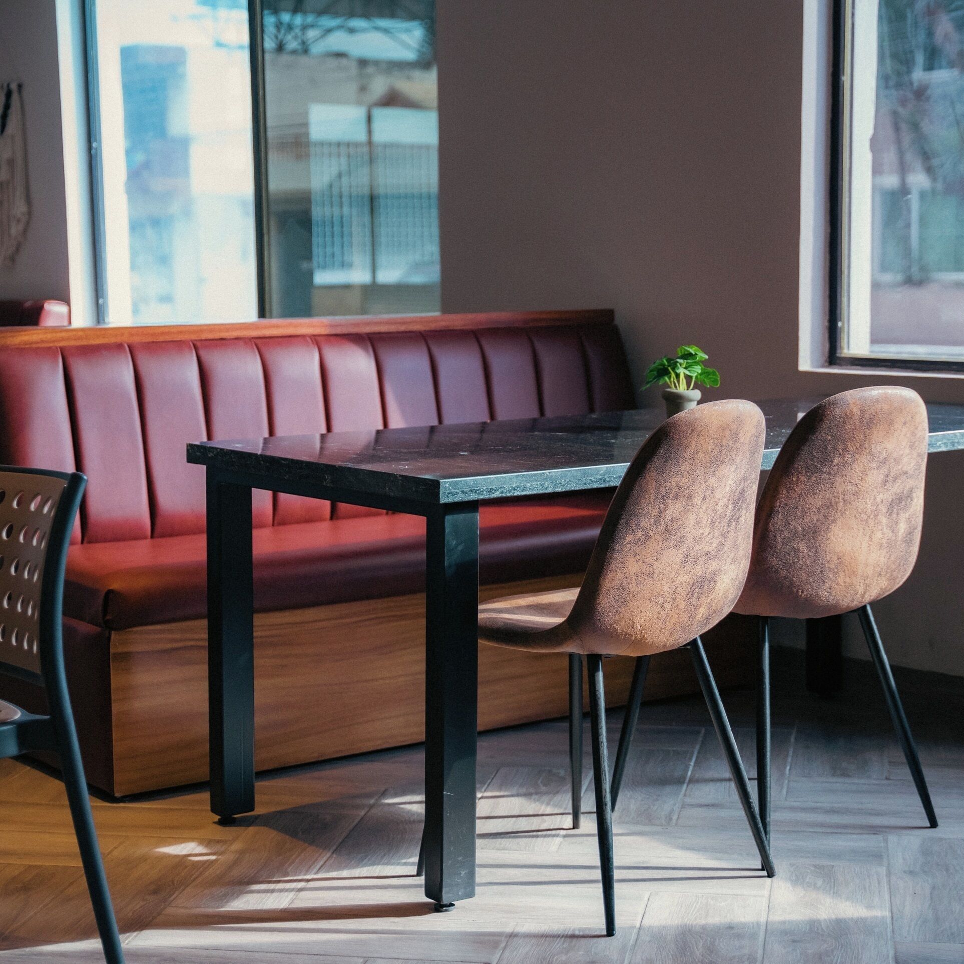 A modern interior with a wooden table, two upholstered chairs, and a red leather bench.