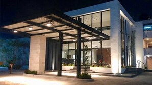 Un edificio moderno con entrada cubierta, ventanas amplias e iluminación exterior.