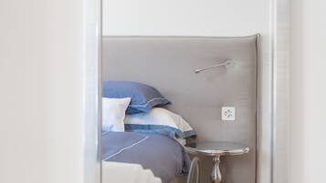 A small, enclosed room with a bed, a round table, and a wall-mounted light fixture.
