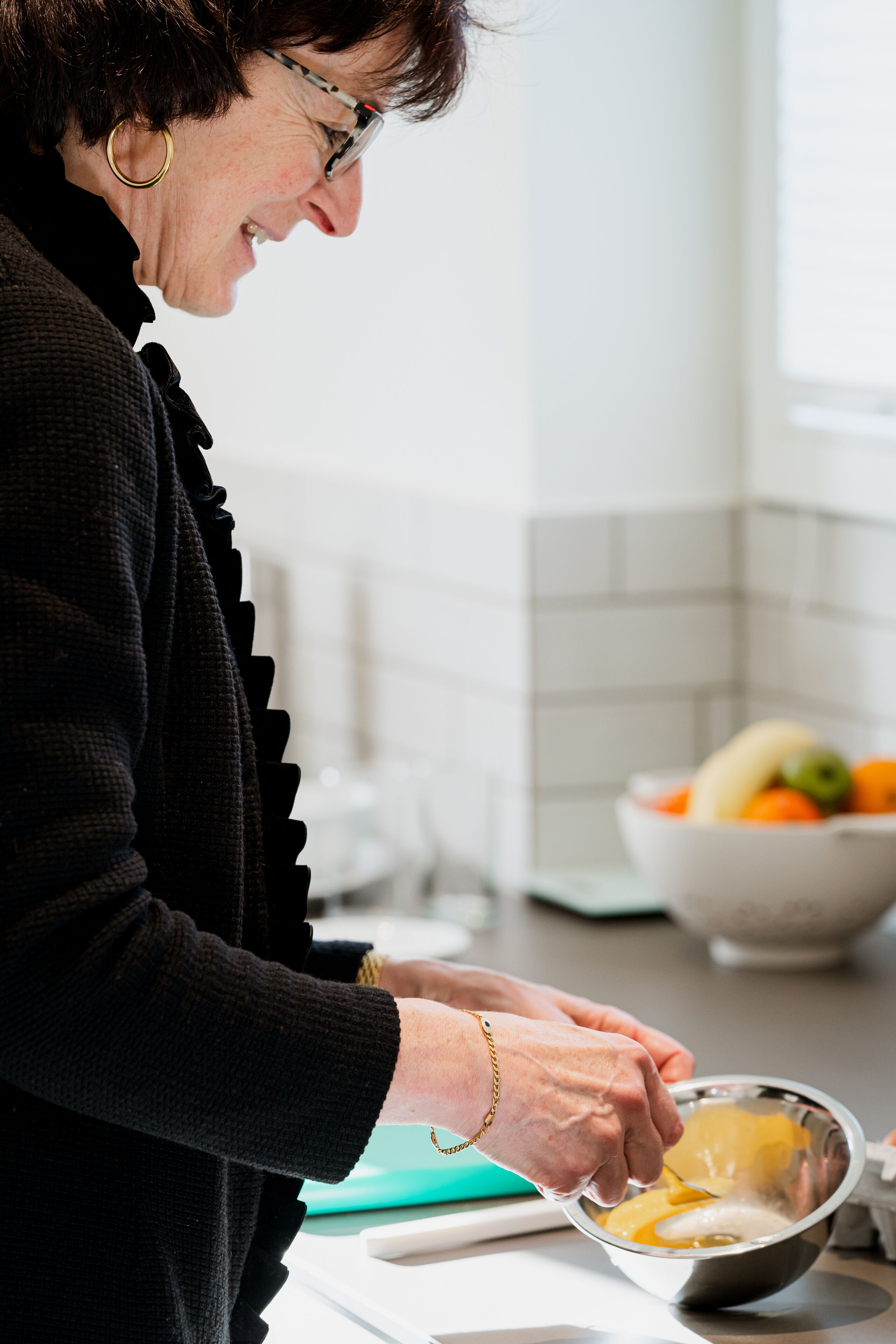 Iemand bereidt eten in een keuken, met een fruitschaal en een snijplank.