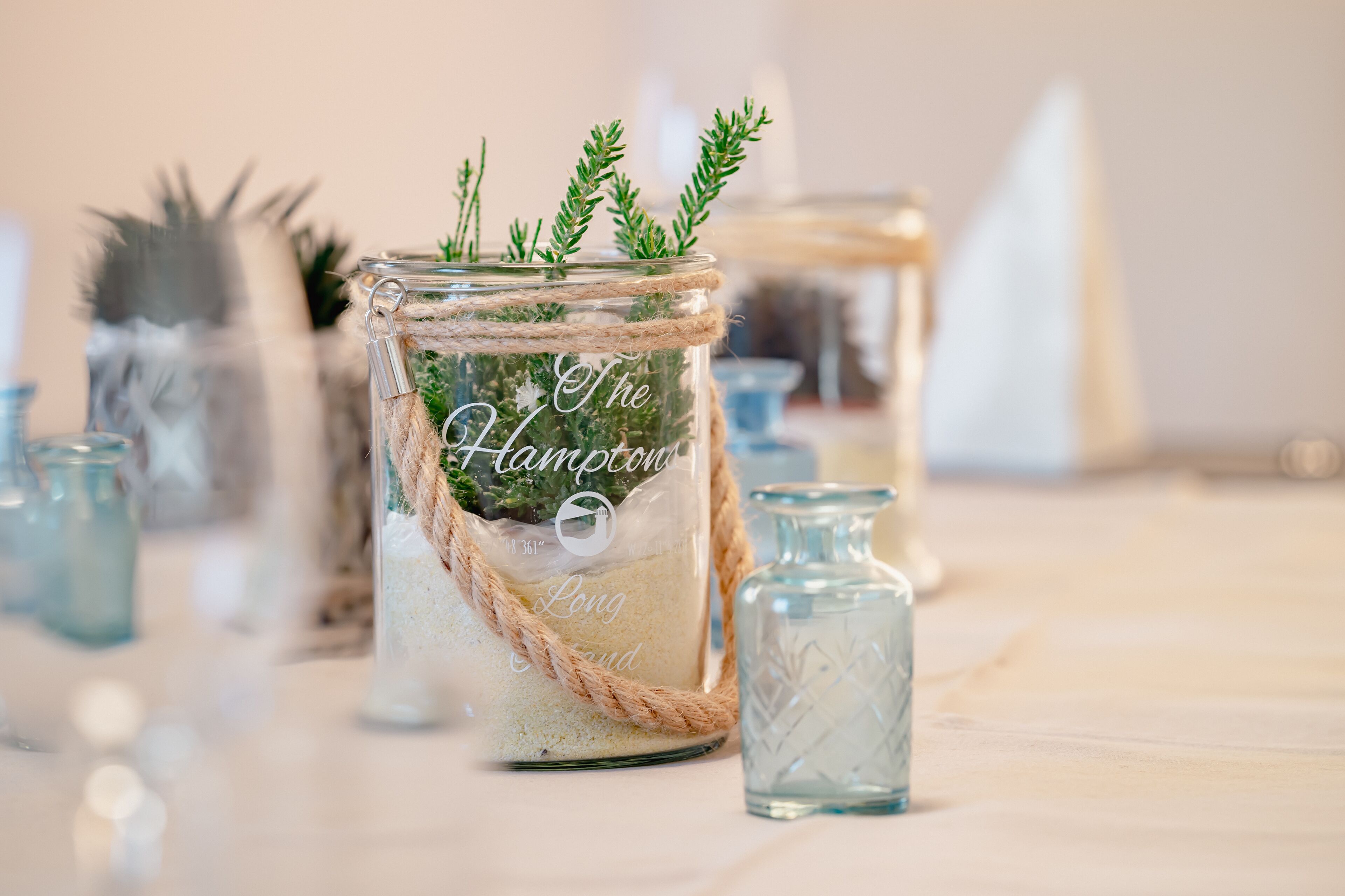Un frasco decorativo con cuerda y follaje, etiquetado como 