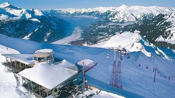 A snow-covered mountain resort with a ski lift, a glass building with a circular top, and a clear view of the surrounding peaks.