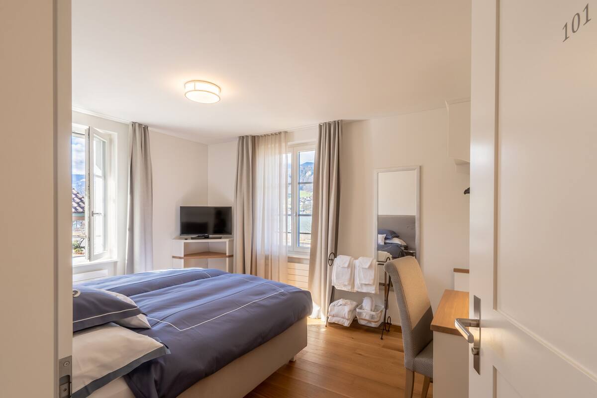 Hotellihuone, jossa on sänky, televisio, työpöytä ja tuoli.