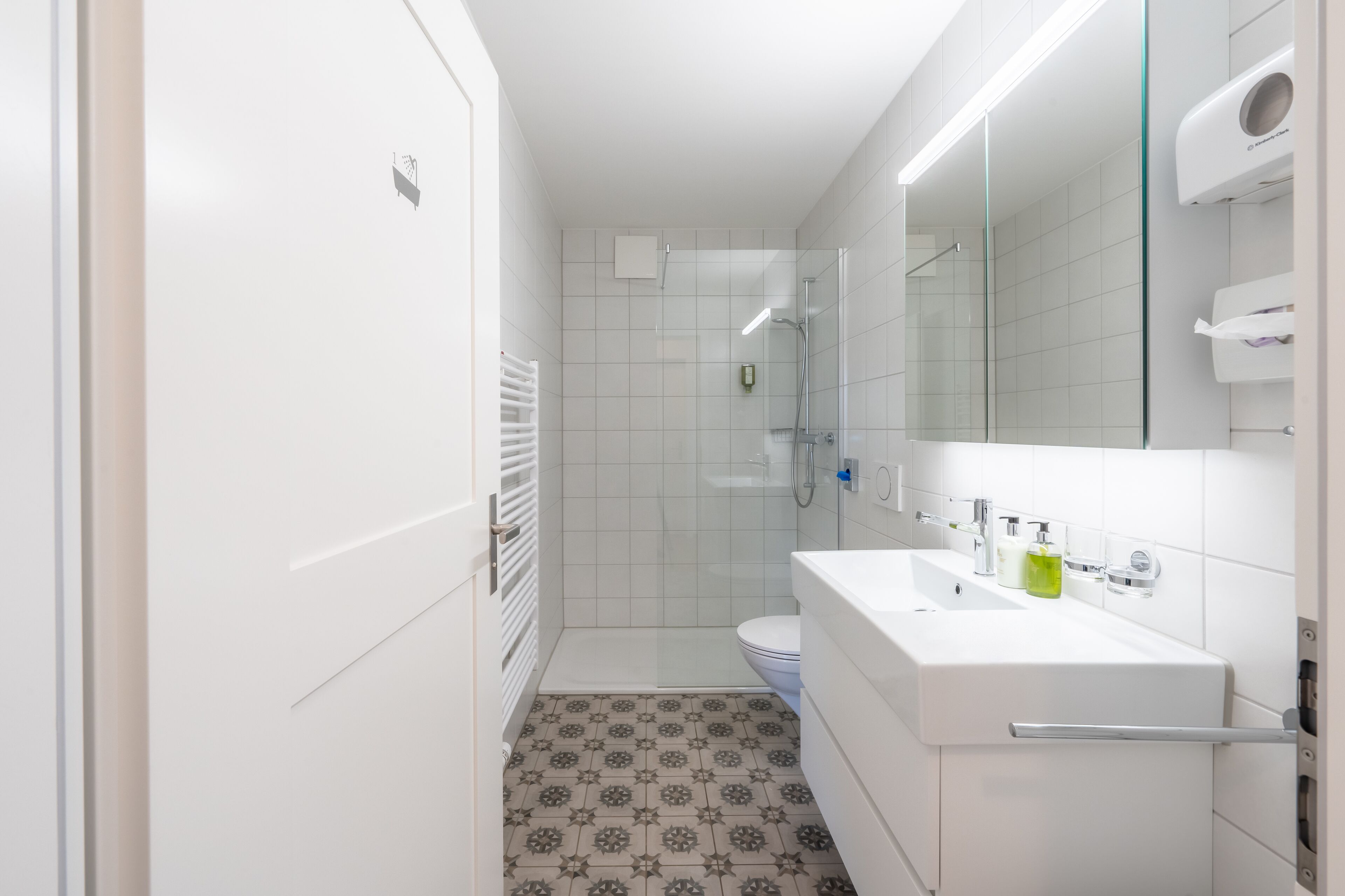 A modern bathroom with a shower, toilet, and sink.