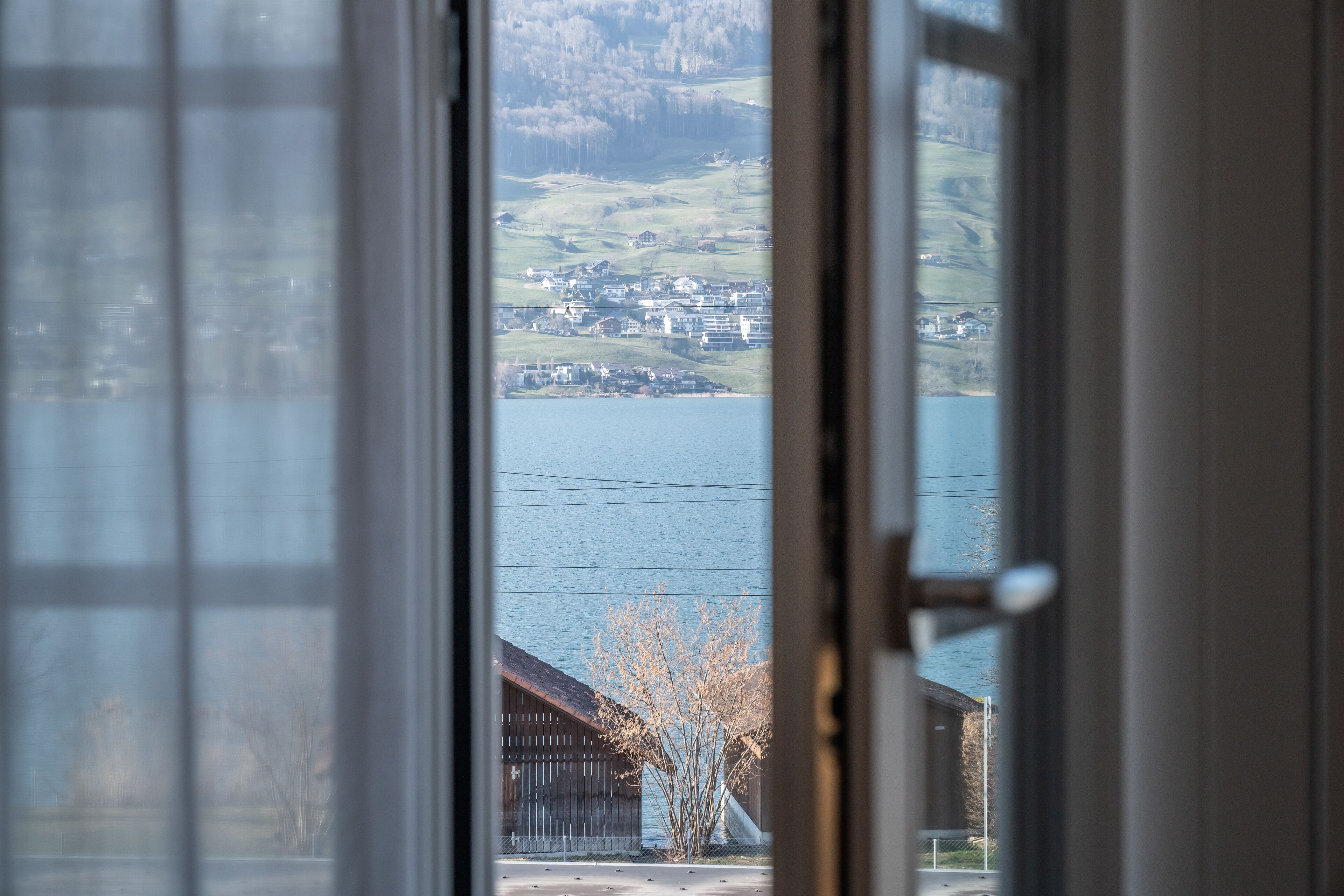Une vue à travers la fenêtre d’un bâtiment, donnant sur un plan d’eau et une ville située au loin.