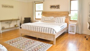 A bedroom with a wooden bed, a bedside table, a chair, a rug, and a wall sign. - The Riverpath Inn, just steps from the Willamette river & Rose Gardens, Eugene (Eugene)