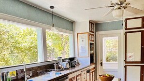 A kitchen with wooden cabinets, a large window, and a ceiling fan. - The Riverpath Inn, just steps from the Willamette river & Rose Gardens, Eugene (Eugene)