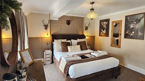 A spacious bedroom with a large bed, a desk with a mirror, and a chandelier. - Creates (Monmouth)