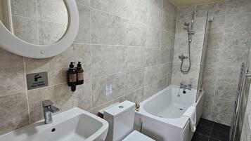 A bathroom with two sinks, a toilet, a bathtub, and a shower.