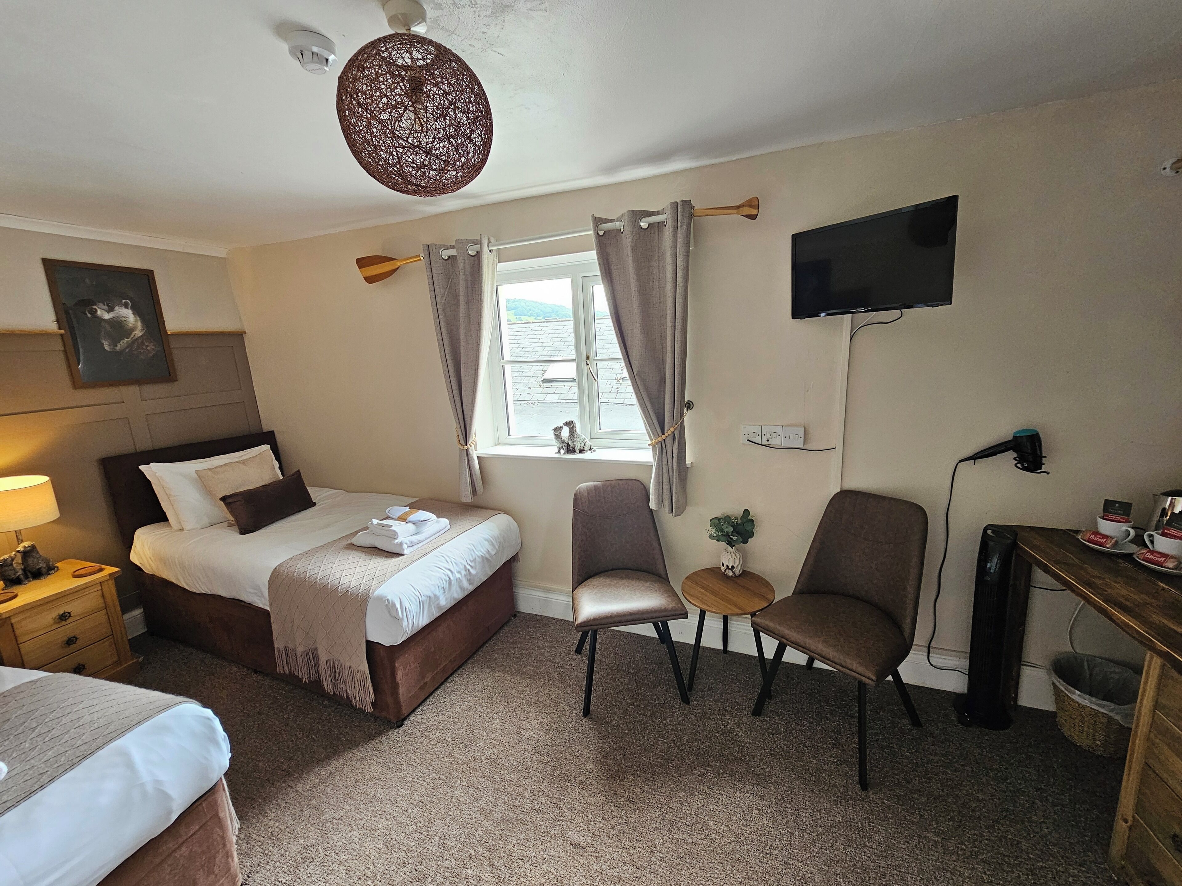 Habitación de hotel con cama, escritorio, silla, televisión y ventana con cortinas.