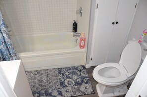 Ein Badezimmer mit Badewanne, Toilette und Duschbereich.