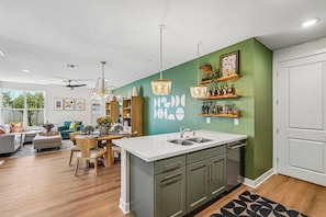 A modern kitchen with a central island, wooden cabinets, and a green accent wall.