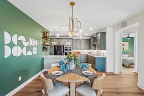 Cozinha moderna com ilha central, sala de jantar com mesa redonda e sala de estar com cama.