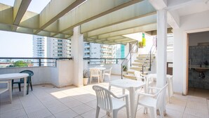 A rooftop terrace with outdoor seating, a staircase, and a view of high-rise buildings. - Hotel Canto do Atlântico (Guarujá)