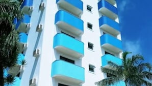 A multi-story building with balconies, a gated entrance, and a staircase leading to the entrance. - Hotel Canto do Atlântico (Guarujá)