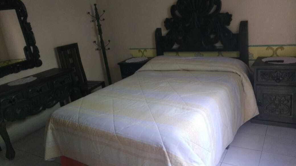 A bedroom with a bed, a dresser, and a mirror.