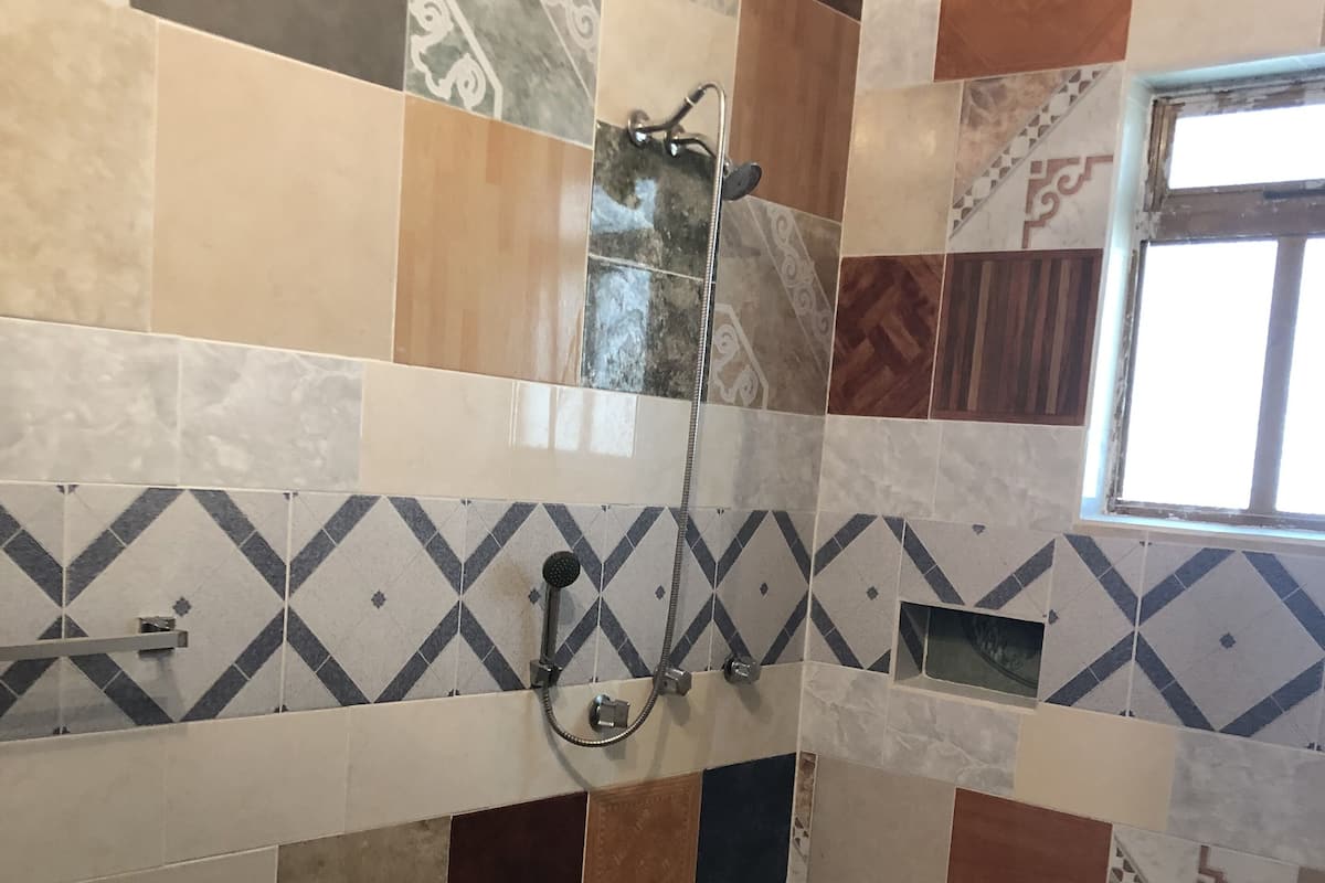 Zona de ducha con pared de azulejos que presenta una variedad de patrones y colores.
